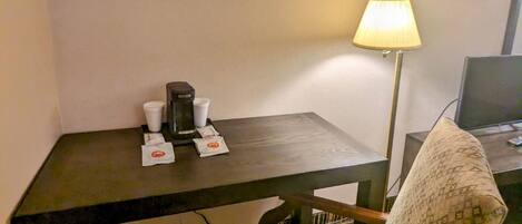 Une chambre d’hôtel équipée d’un bureau, d’une chaise, d’une lampe et d’un tableau encadré au mur.