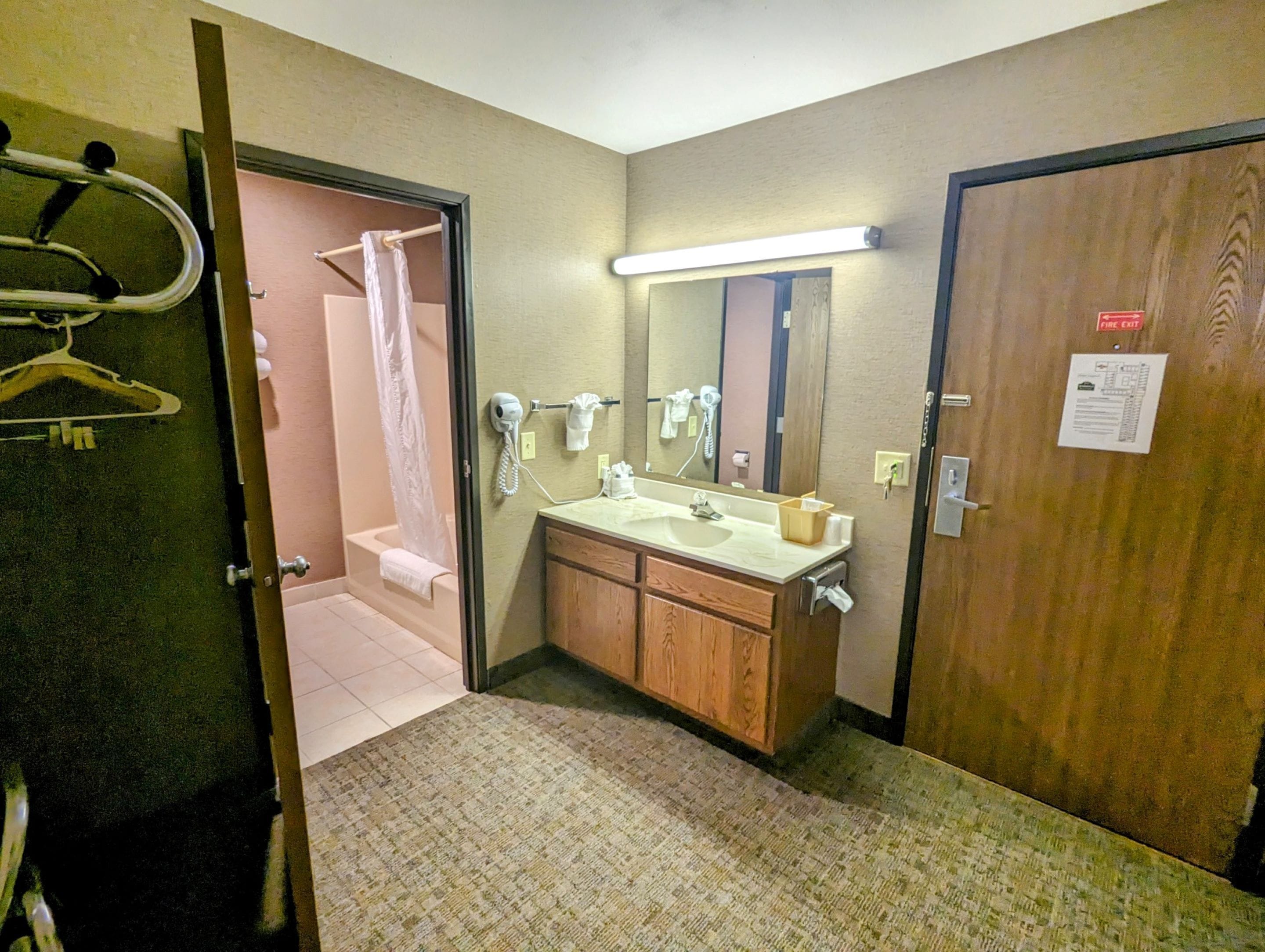Un baño de hotel con ducha, lavamanos y espejo.
