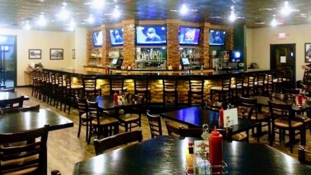 A bar area with multiple TVs, a counter, and several tables and chairs. - Woodfield Inn and Suites (Marshfield)