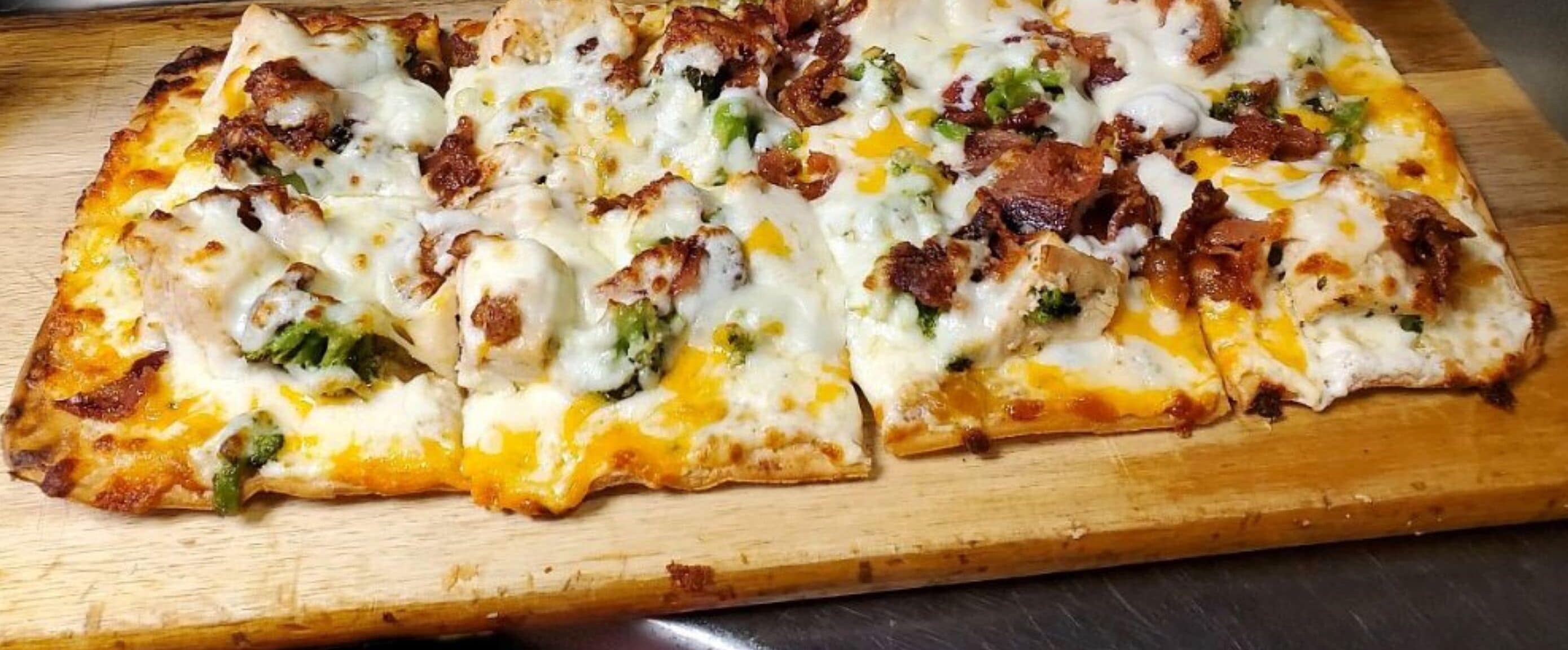 A pizza with various toppings on a wooden cutting board.