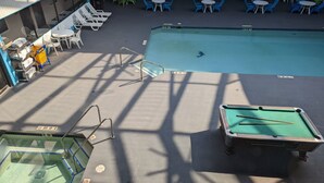 A pool area with lounge chairs, a pool table, and a diving board. - Woodfield Inn and Suites (Marshfield)