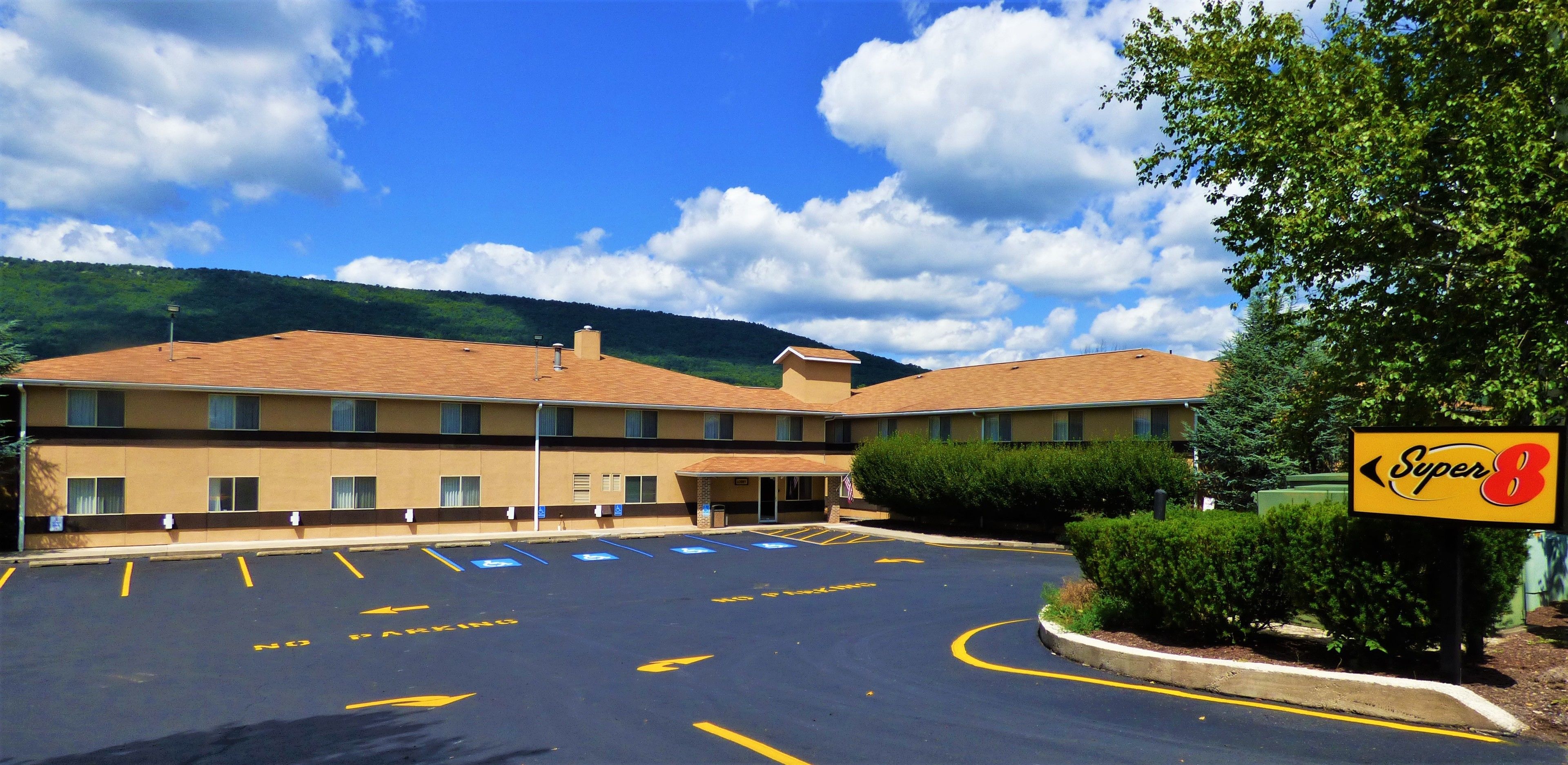 A motel with a parking lot, a Super 8 sign, and a mountain backdrop.