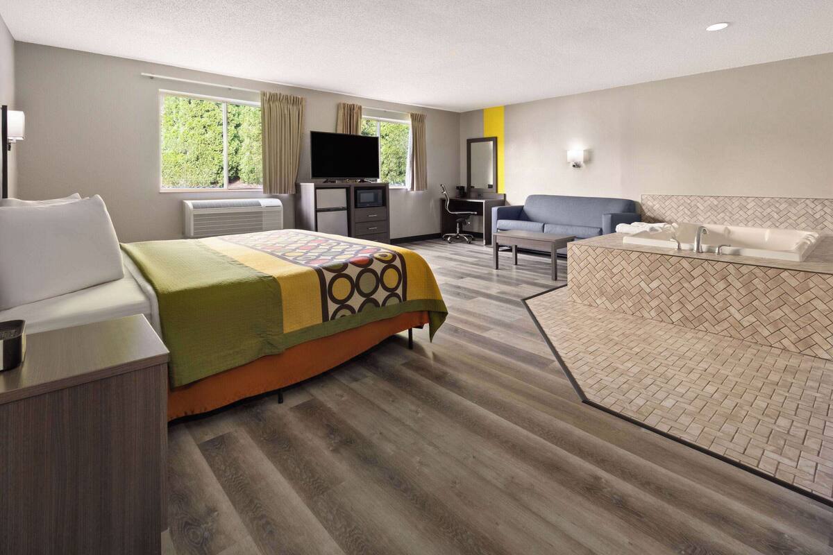 Ein Hotelzimmer mit Bett, Schreibtisch, Stuhl, Fernseher und Badezimmer.