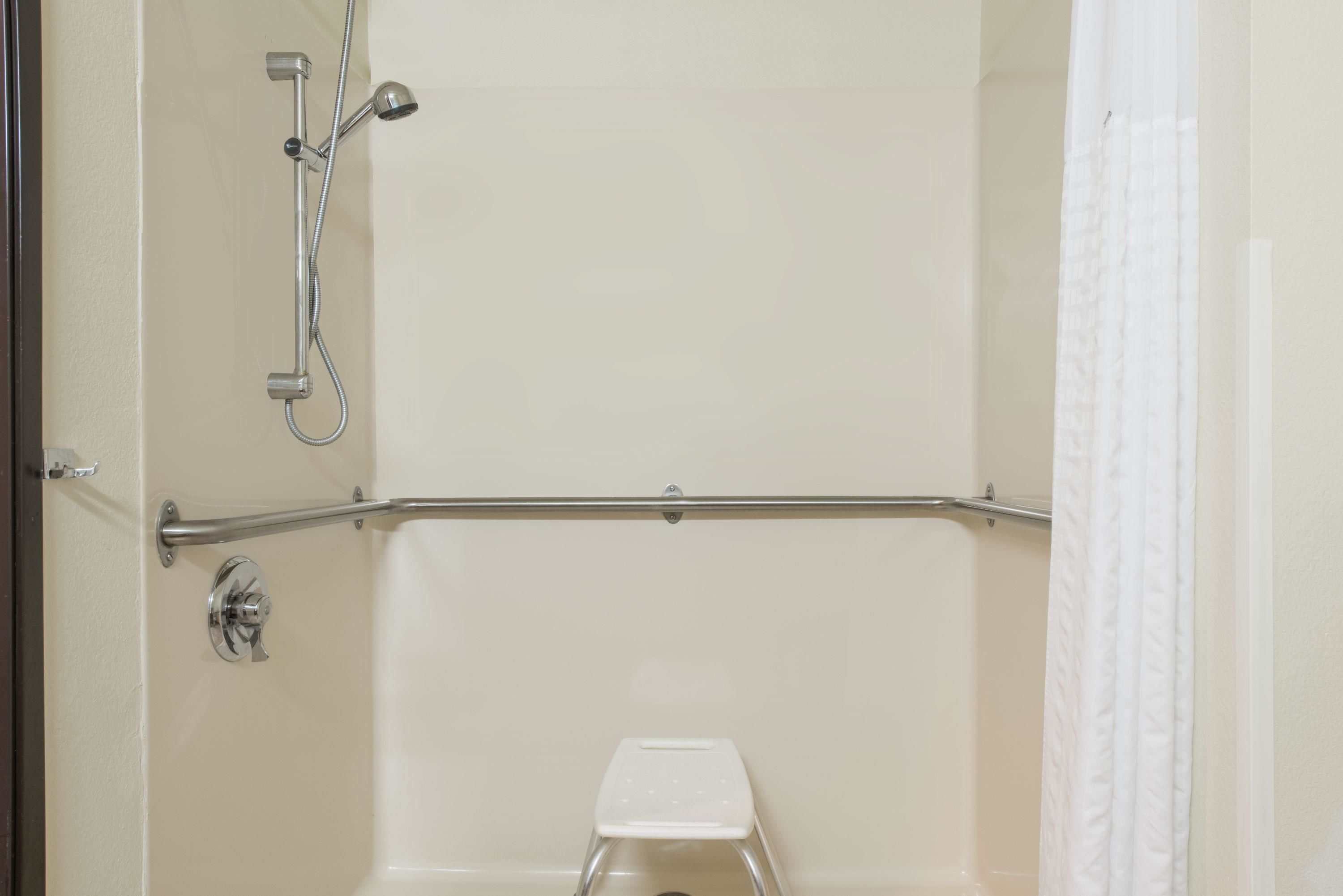 Une salle de bain équipée d’une douche, de toilettes et d’une barre d’appui.