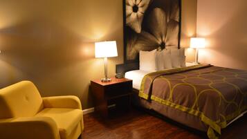 Una habitación de hotel con una cama, dos lámparas de noche, una mesita de noche, un sillón amarillo y una obra de arte floral grande en la pared.