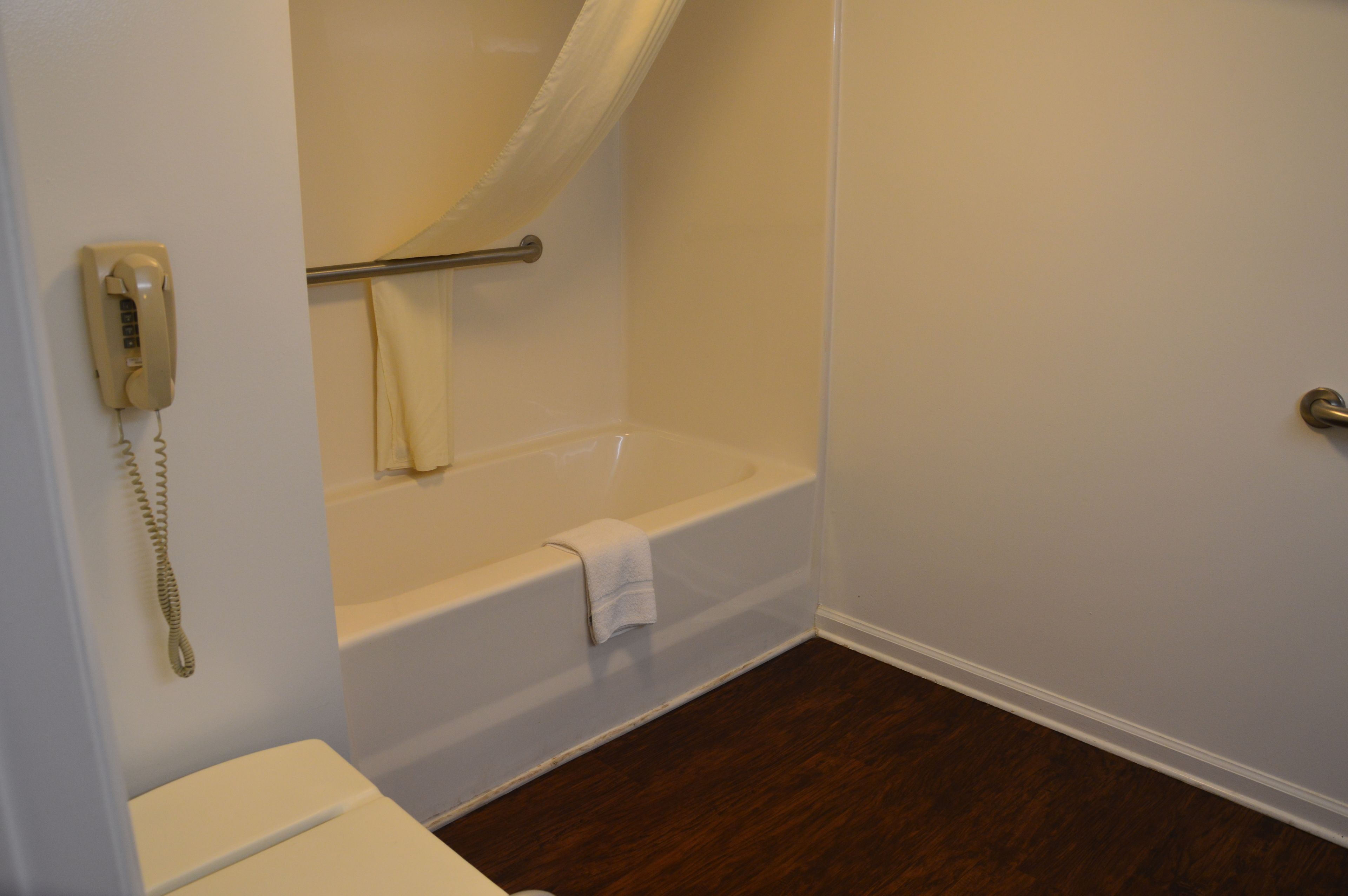A bathroom with a bathtub, a toilet, and a telephone.