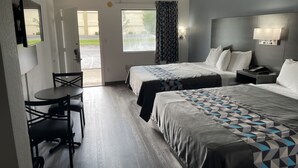 A hotel room with two beds, a desk, and a chair.