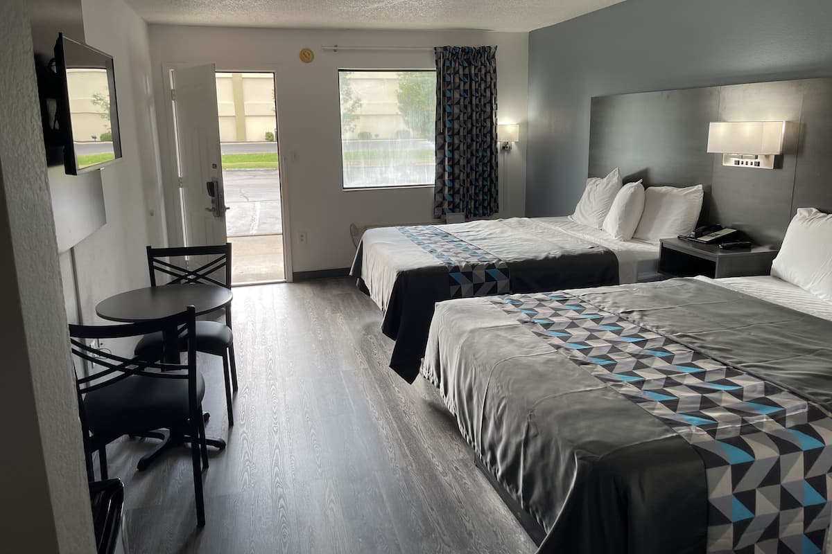 A hotel room with two beds, a desk, and a chair.
