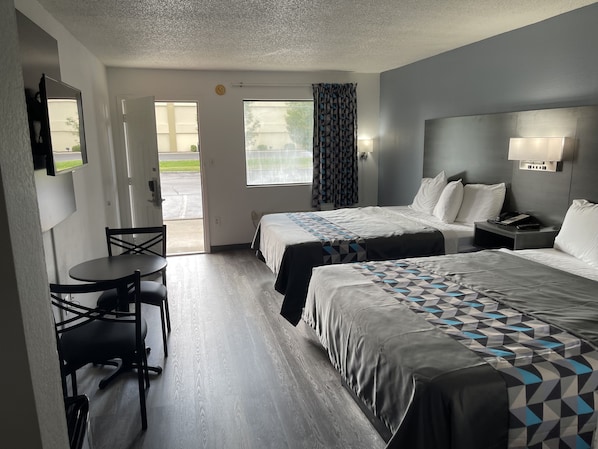 Habitación de hotel con dos camas, un escritorio y una silla.