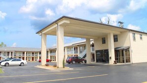A motel with a covered parking area, multiple-story buildings, and a clear sky.