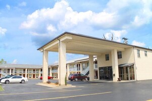 Un motel con estacionamiento techado, edificios de varios pisos y cielo despejado.