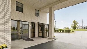 A modern building with a brick facade, large glass doors, and a covered entrance area.