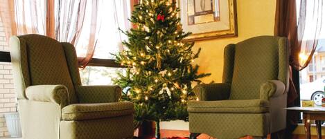 A room with two armchairs, a Christmas tree, and a framed picture on the wall.