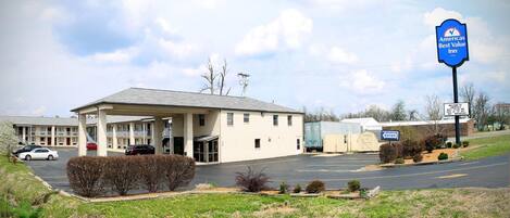 Un motel doté d’un grand parking, d’un espace extérieur abrité et d’une enseigne indiquant qu’il s’agit d’un établissement de la chaîne AmericBest Value Inn.