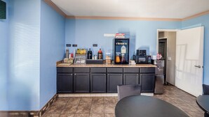 Une cuisine de taille réduite, dotée de meubles de rangement sombres, d’une machine à café et d’un réfrigérateur.