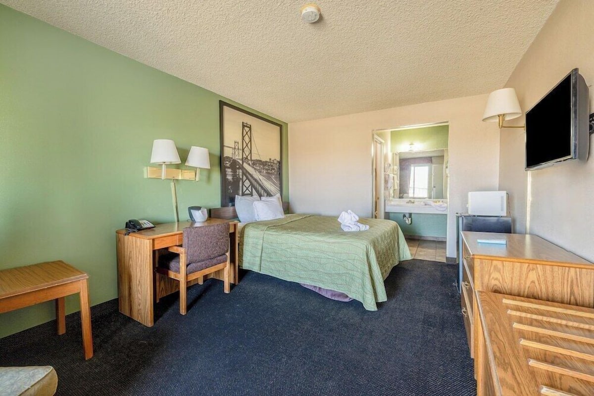 Une chambre d’hôtel équipée d’un lit, d’un bureau, d’une chaise et d’un téléviseur.