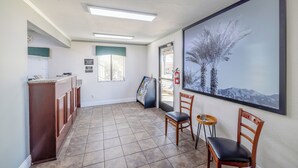 Un espace d’accueil comprenant un comptoir de réception, des chaises, un grand tableau encadré et un panneau d’affichage.