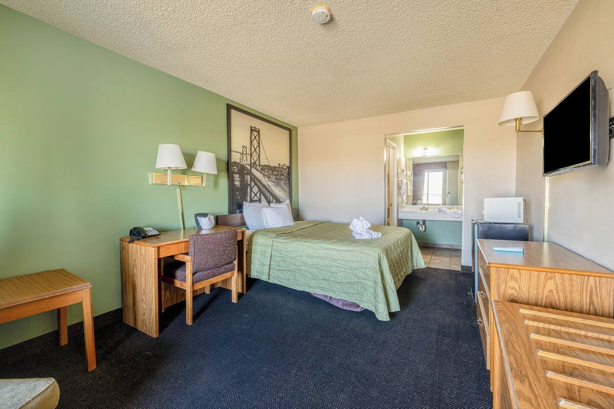 Une chambre d’hôtel équipée d’un lit, d’un bureau, d’une chaise et d’un téléviseur.
