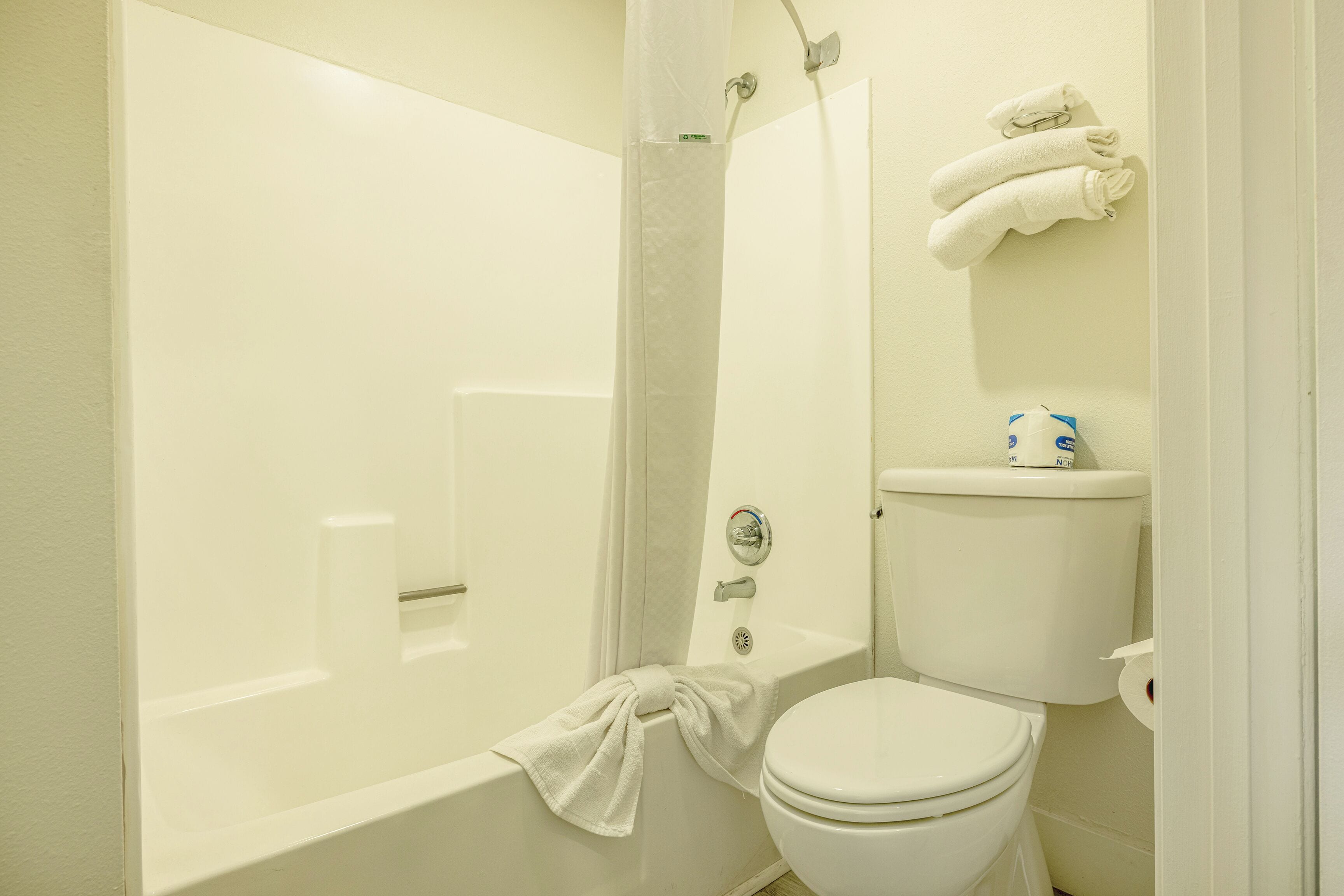 Baño con bañera, inodoro y un perchero para toallas.