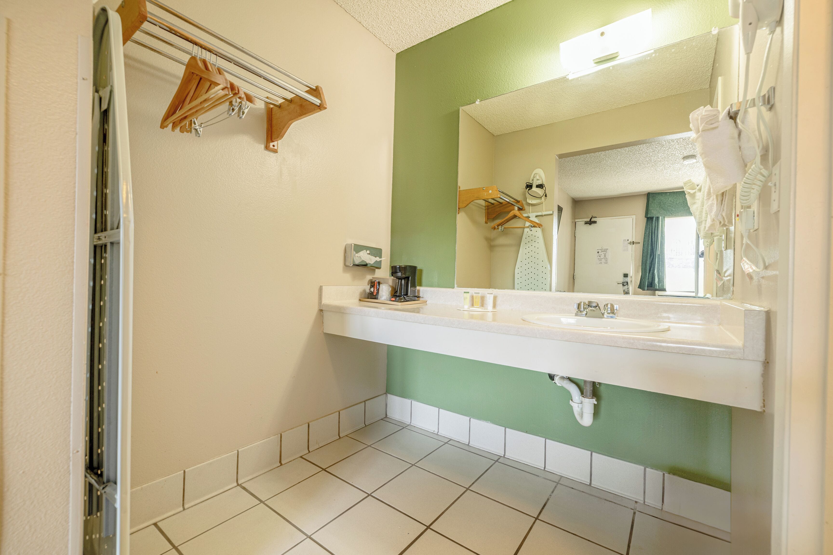 A bathroom with a white sink, green wall, and a mirror.