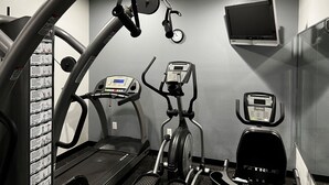 Un gimnasio con cintas de correr, elípticas y una bicicleta estática.
