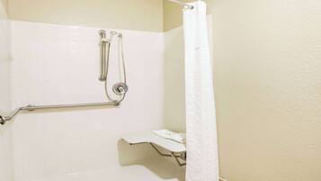 Baño con ducha, barra de apoyo y asiento.