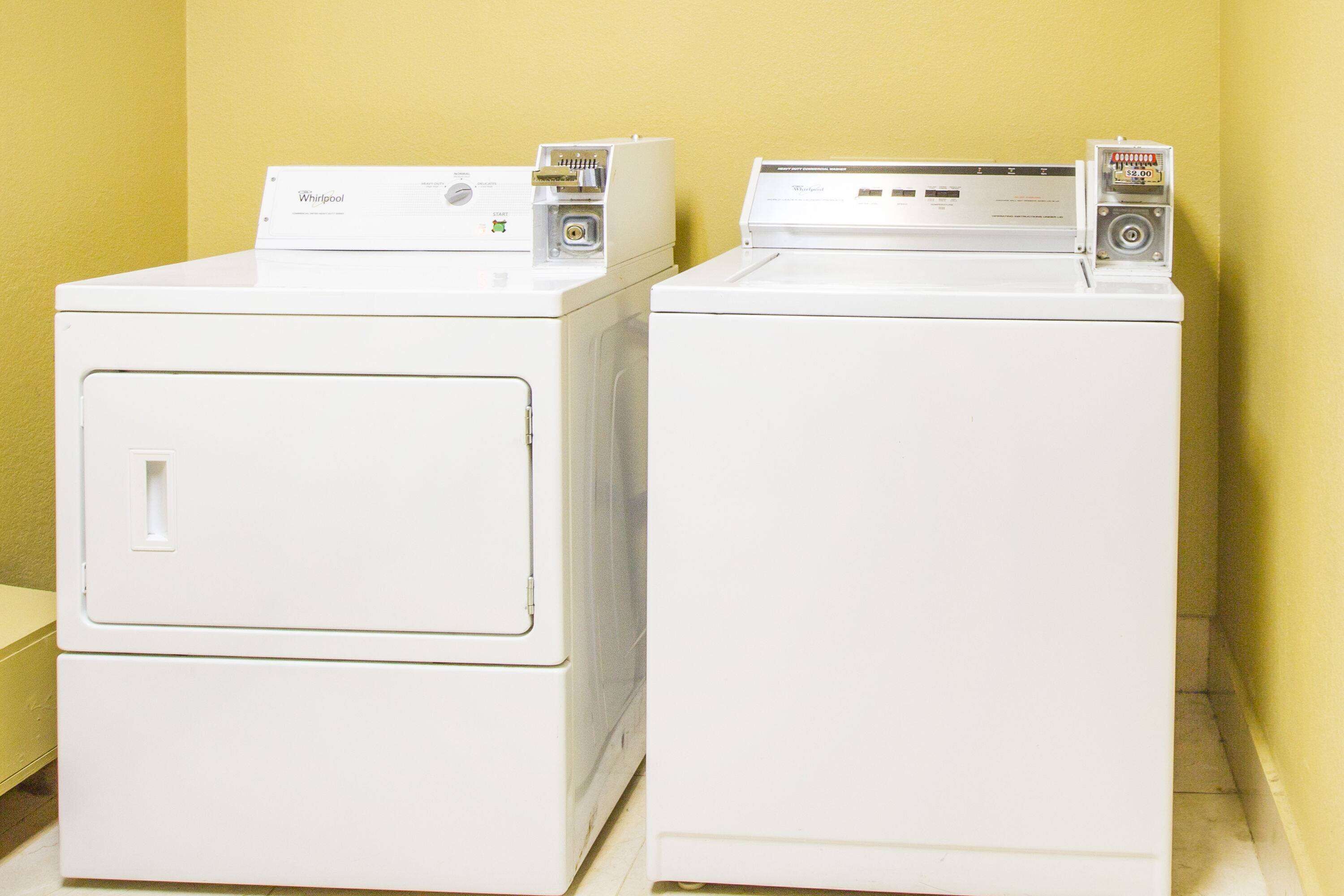 Dos lavadoras Whirlpool de carga frontal, de color blanco, en una habitación con paredes amarillas.