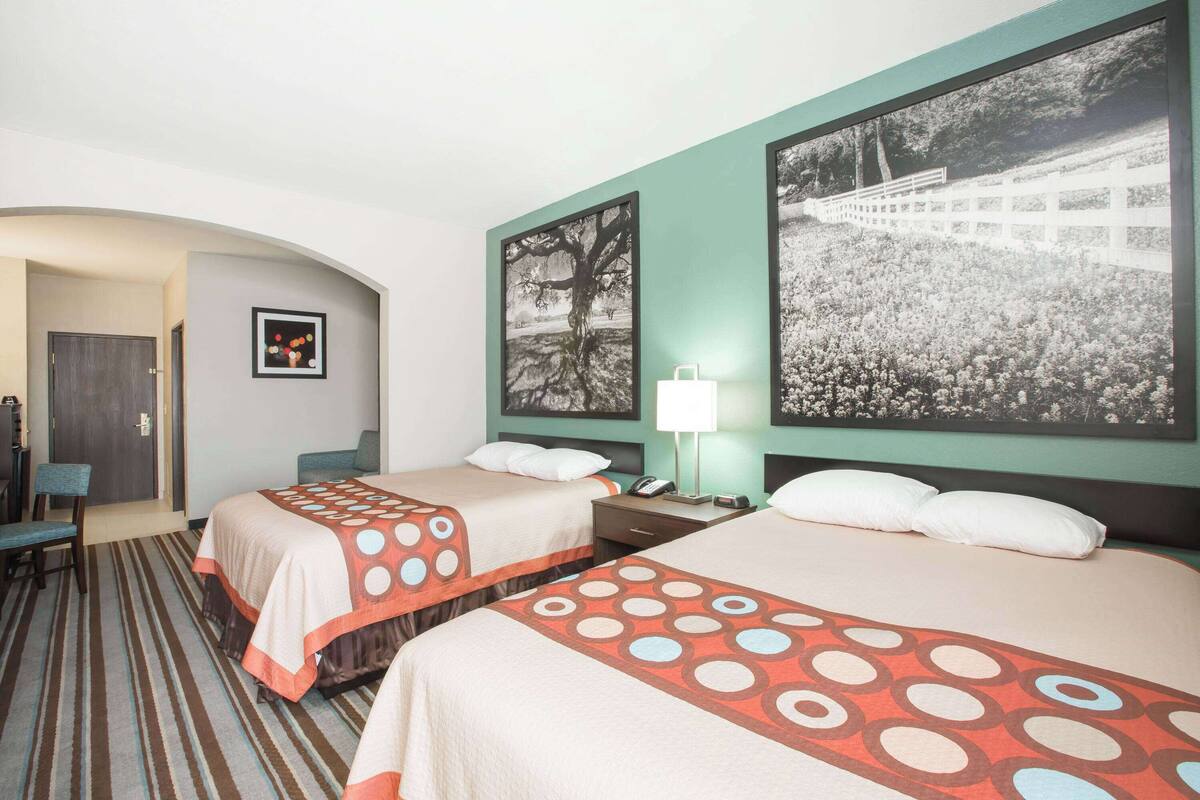 Habitación de hotel con dos camas, un escritorio, una silla y un ventanal grande.