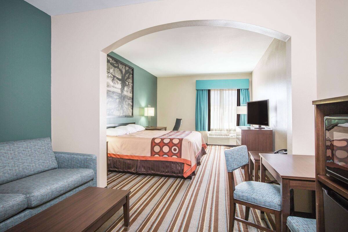 Una habitación de hotel con cama, sofá, televisión y escritorio.