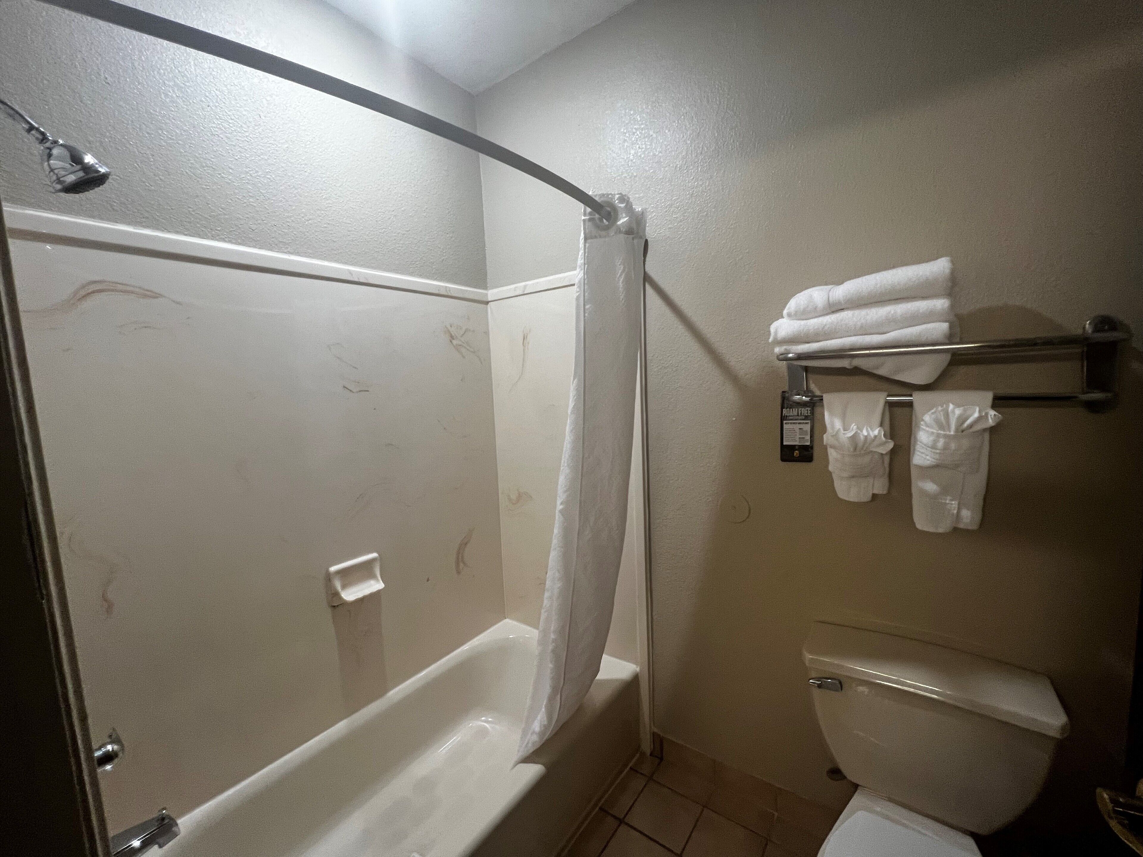 A bathroom with a bathtub, toilet, and a towel rack with towels.