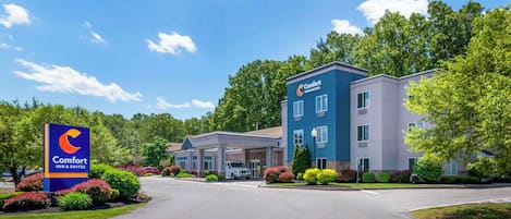Un hôtel Comfort Inn & Suites à l’extérieur bleu et blanc, doté d’un parking couvert et d’un espace paysager verdoyant.