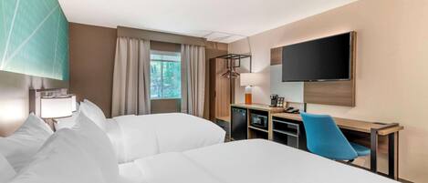 A hotel room with two beds, a desk with a computer, a TV, and a window with curtains.