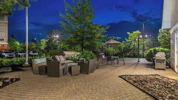 An outdoor patio area with wicker furniture, a barbecue grill, and a paved walkway. - Residence Inn by Marriott Toronto Markham (Markham)