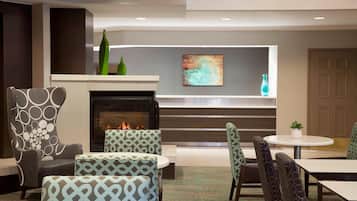 A modern lounge area with patterned armchairs, a fireplace, and a contemporary art piece on the wall.