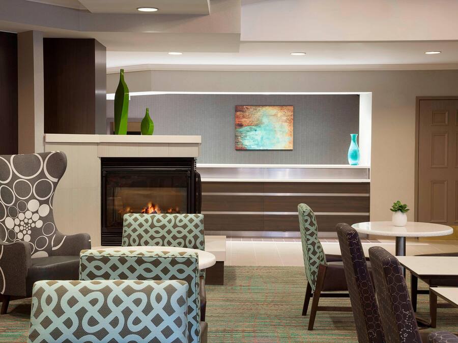 A modern lounge area with patterned armchairs, a fireplace, and a contemporary art piece on the wall.