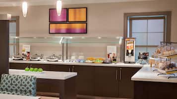 Un espace pour le petit-déjeuner à l’hôtel, avec un buffet, des tables et des œuvres d’art accrochées aux murs.
