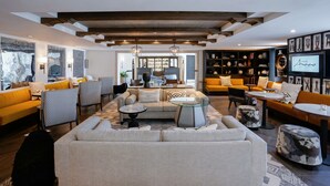 A modern living room with a sofa set, a coffee table, and a bookshelf. - Hotel Amarano Burbank - Hollywood (Burbank)
