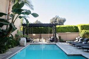 Una piscina al aire libre, sombrillas, sillones reclinables de piscina