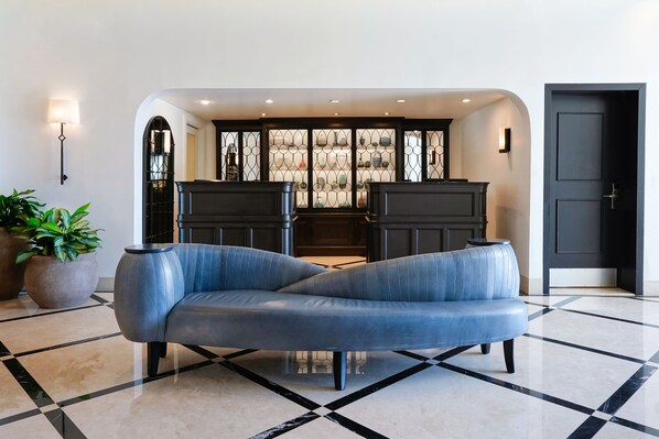 A modern living room with a blue sofa, a fireplace, and a decorative wall panel.