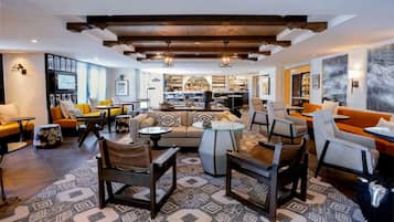 A modern living room with a sofa, chairs, a coffee table, and a bar area in the background.