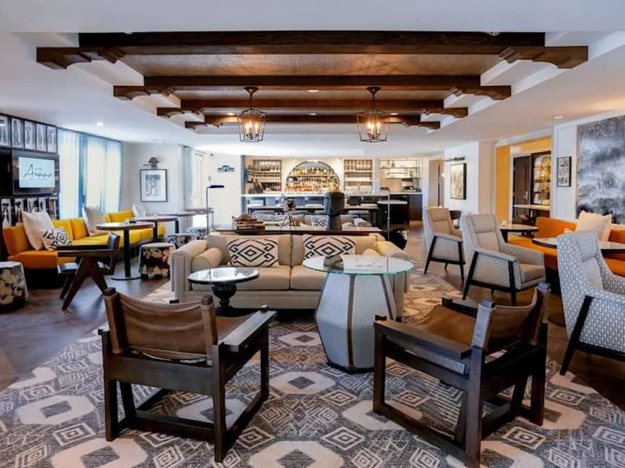 Una sala de estar moderna con un sofá, sillas, una mesita de centro y una zona de bar al fondo.