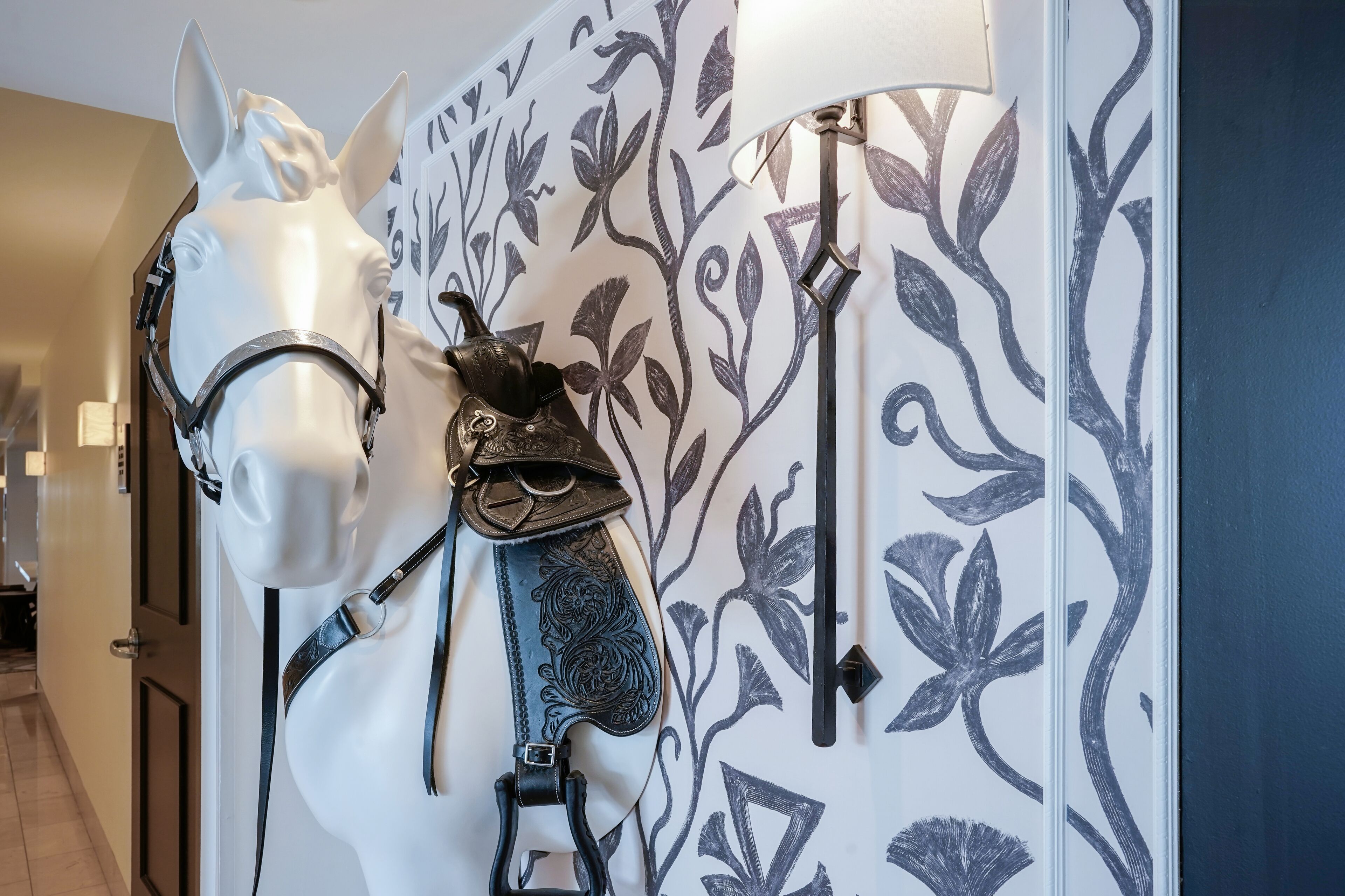 A room with a decorative wall featuring a floral pattern and a mounted horse head sculpture.