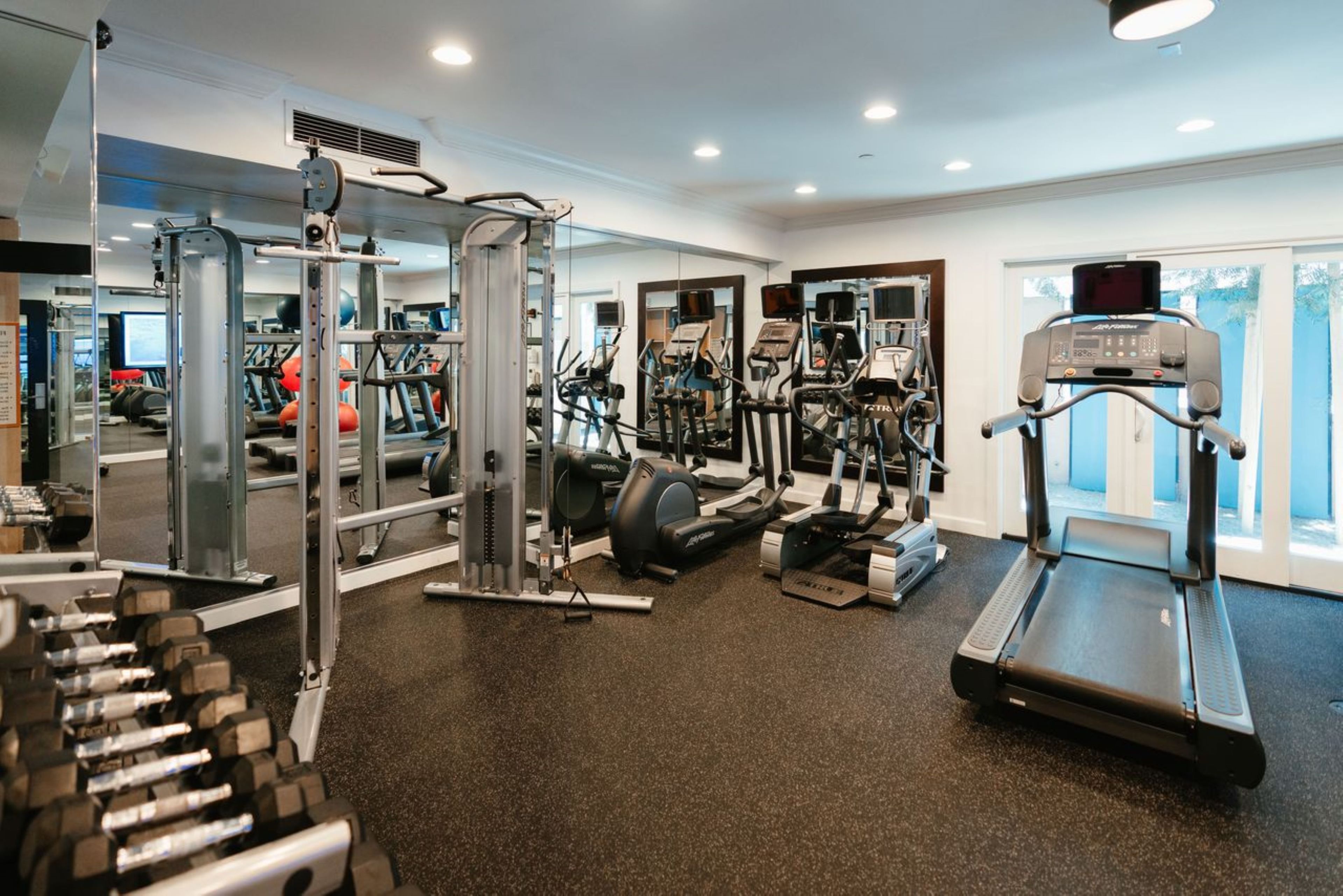A gym with various exercise equipment including treadmills, weight machines, and free weights.