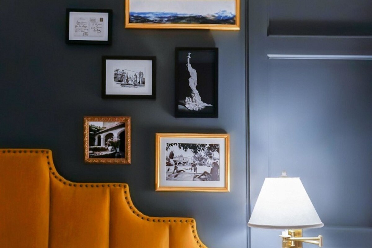Une pièce comprenant un lit, une table de chevet, une lampe et des tableaux encadrés accrochés au mur.