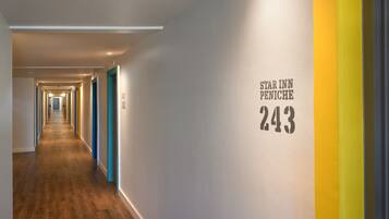 A hotel corridor with a wooden floor and walls painted in white, blue, and yellow. The number 243 is displayed on the wall.