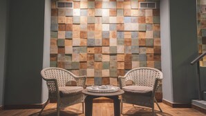A room with two wicker chairs, a small round table with a tray, and a wall with a checkered pattern of wooden tiles. - Star Inn Peniche (Peniche)