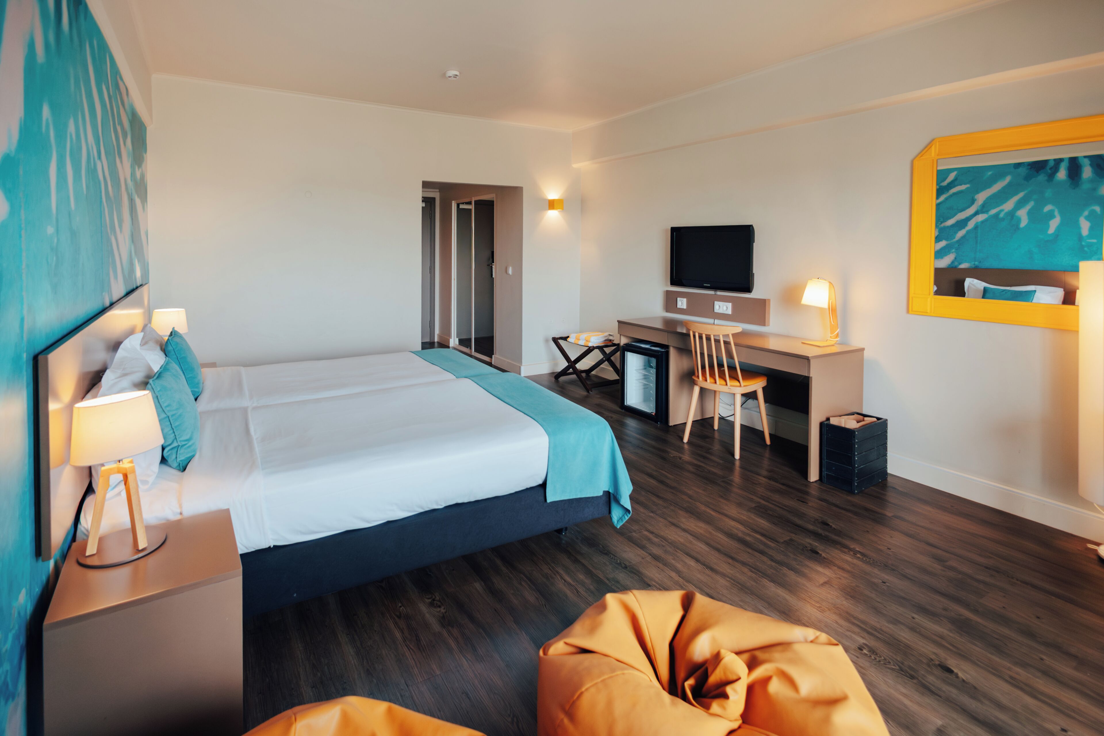 Habitación de hotel con cama, escritorio, silla, televisor y una pequeña zona de estar.