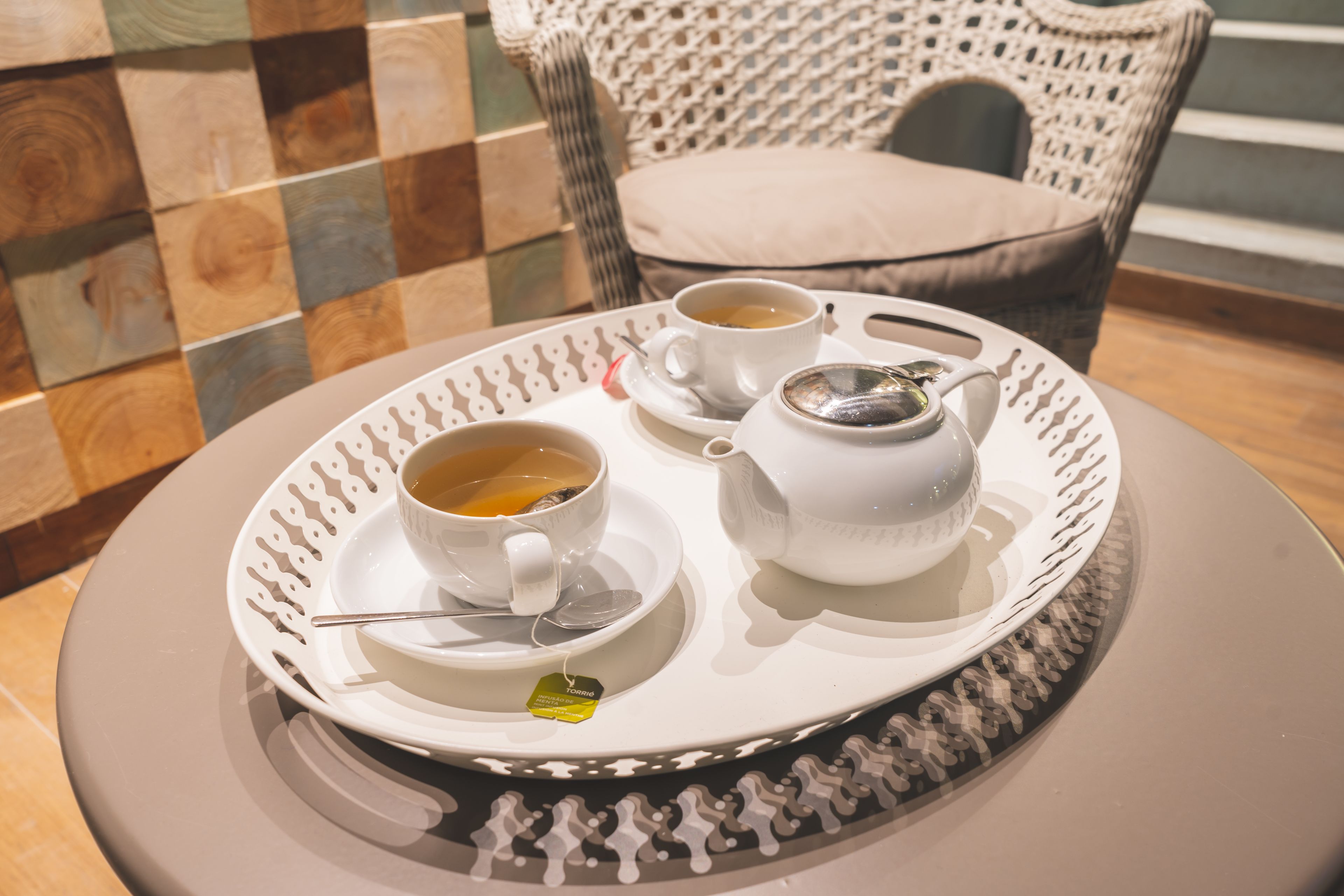 Una bandeja con dos tazas de té y una tetera sobre una mesa redonda.
