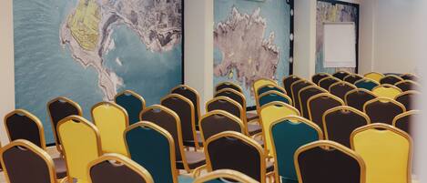 A conference room with rows of chairs, a large map on the wall, and a whiteboard.