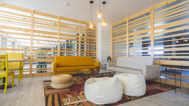 A modern living room with a yellow sofa, white bean bags, and a patterned rug. - Star Inn Peniche (Peniche)